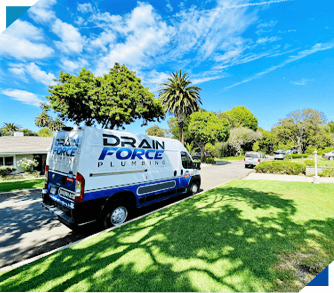 A Drain Force Plumbing van is parked on a suburban street with houses, trees, and a clear blue sky in the background.
